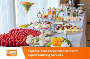 Corporate event catering table with desserts, fruits, and beverages by laptop lunch catering in dubai